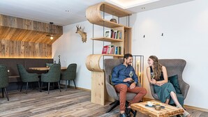 A modern interior with a wooden bookshelf, seating area, and a dining space.