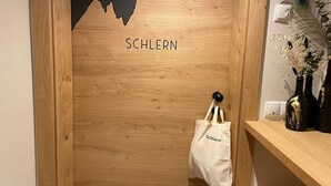A wooden door with the word 'SCHLERN' on it, a white tote bag hanging on a hook, and a vase with flowers on a shelf. - "Schlern" with Mountain View, Whirlpool, Finnish Sauna & Steam Sauna & Balcony (Deutschnofen)