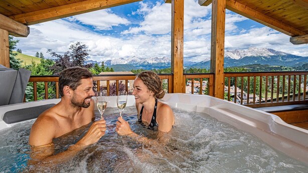 A couple in a hot tub with a mountain view. - "Schlern" with Mountain View, Whirlpool, Finnish Sauna & Steam Sauna & Balcony (Deutschnofen)