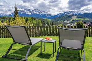 Two outdoor chairs with a table, a wooden fence, and a mountain view. - "Schlern" with Mountain View, Whirlpool, Finnish Sauna & Steam Sauna & Balcony (Deutschnofen)