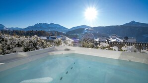 Ein Pool mit Blick auf einen Berg, umgeben von schneebedeckten Bäumen und Gebäuden.