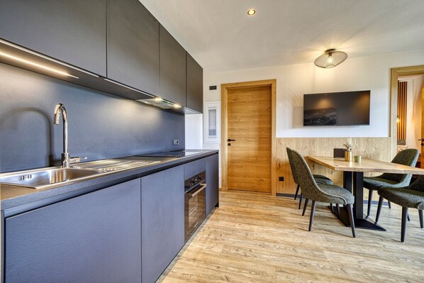 Una cocina moderna con estufa integrada, un lavamanos de acero inoxidable y una puerta de madera.