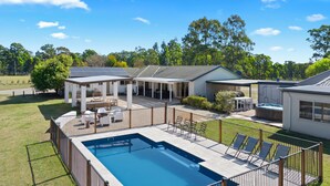 Propiedad residencial con piscina, zona de estar al aire libre y porche cubierto.