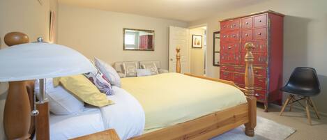 A bedroom with a wooden bed, a bedside table with a lamp, a wardrobe, and a chair.