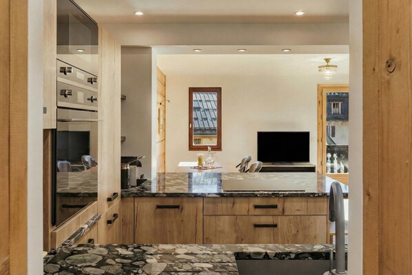 Une cuisine moderne dotée d’un plan de travail en marbre, de meubles en bois et d’un téléviseur encastré.