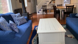A living room with blue sofas, a white coffee table, a fireplace, and a staircase leading to a dining area. - Block Island The Way It Used To Be!!!  Steps From Everything!!! (New Shoreham)