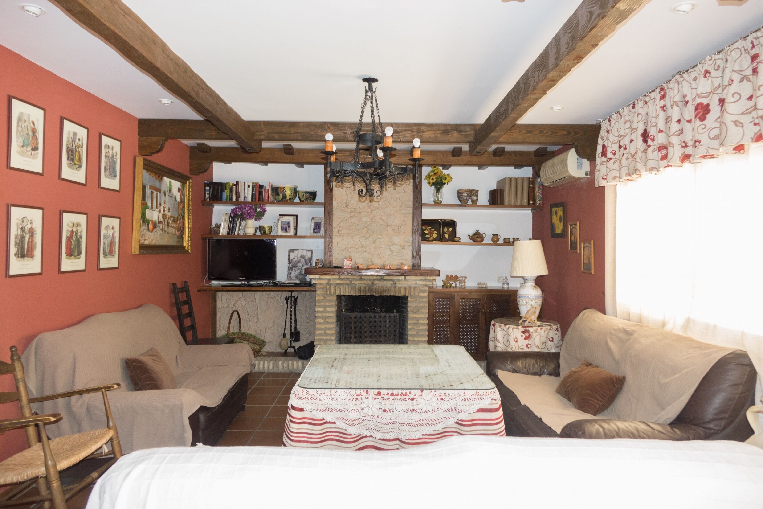 A cozy living room with a fireplace, wooden beams, a television, and a comfortable seating area.