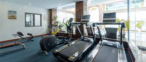 A hotel gym with treadmills, elliptical machines, and weight benches.