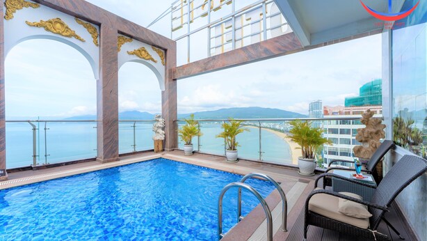 A rooftop infinity pool with a glass balustrade, potted plants, and a wicker chair. - Vietnam Taste Hotel Quy Nhon - Beachfront (Quy Nhon)
