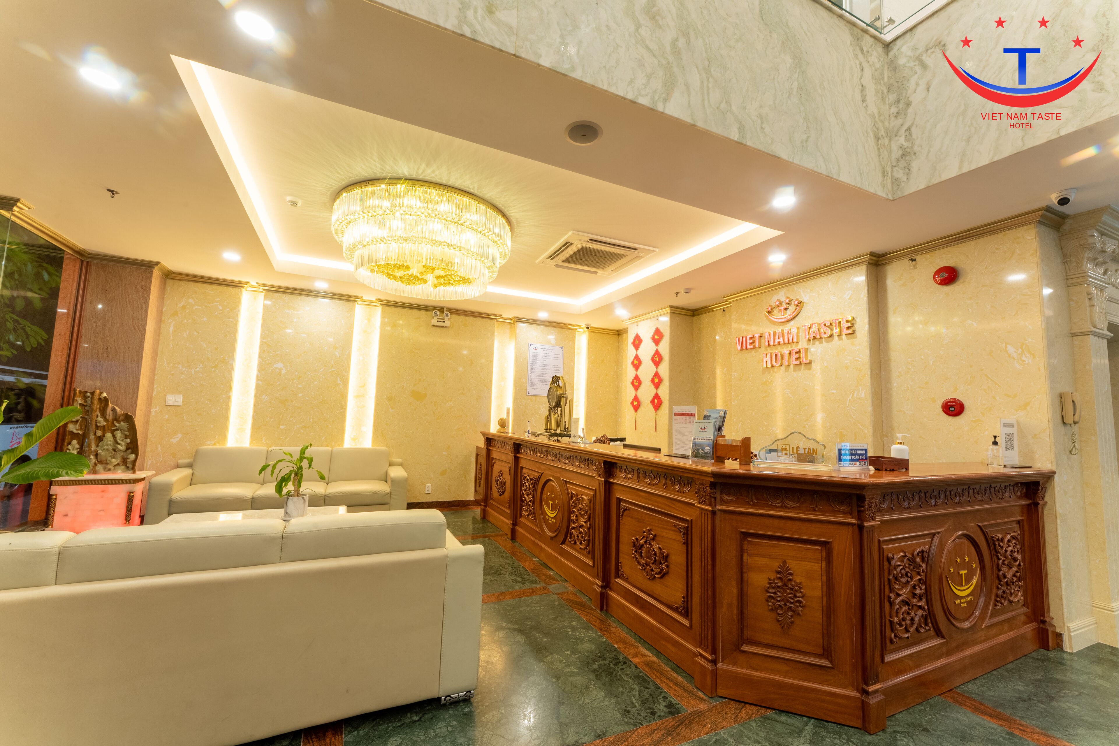A hotel reception area with a marble reception desk, a chandelier, and a sign for the Viet Nam Taste Hotel.