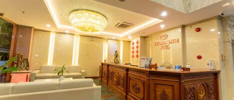 A hotel reception area with a marble reception desk, a chandelier, and a sign for the Viet Nam Taste Hotel.