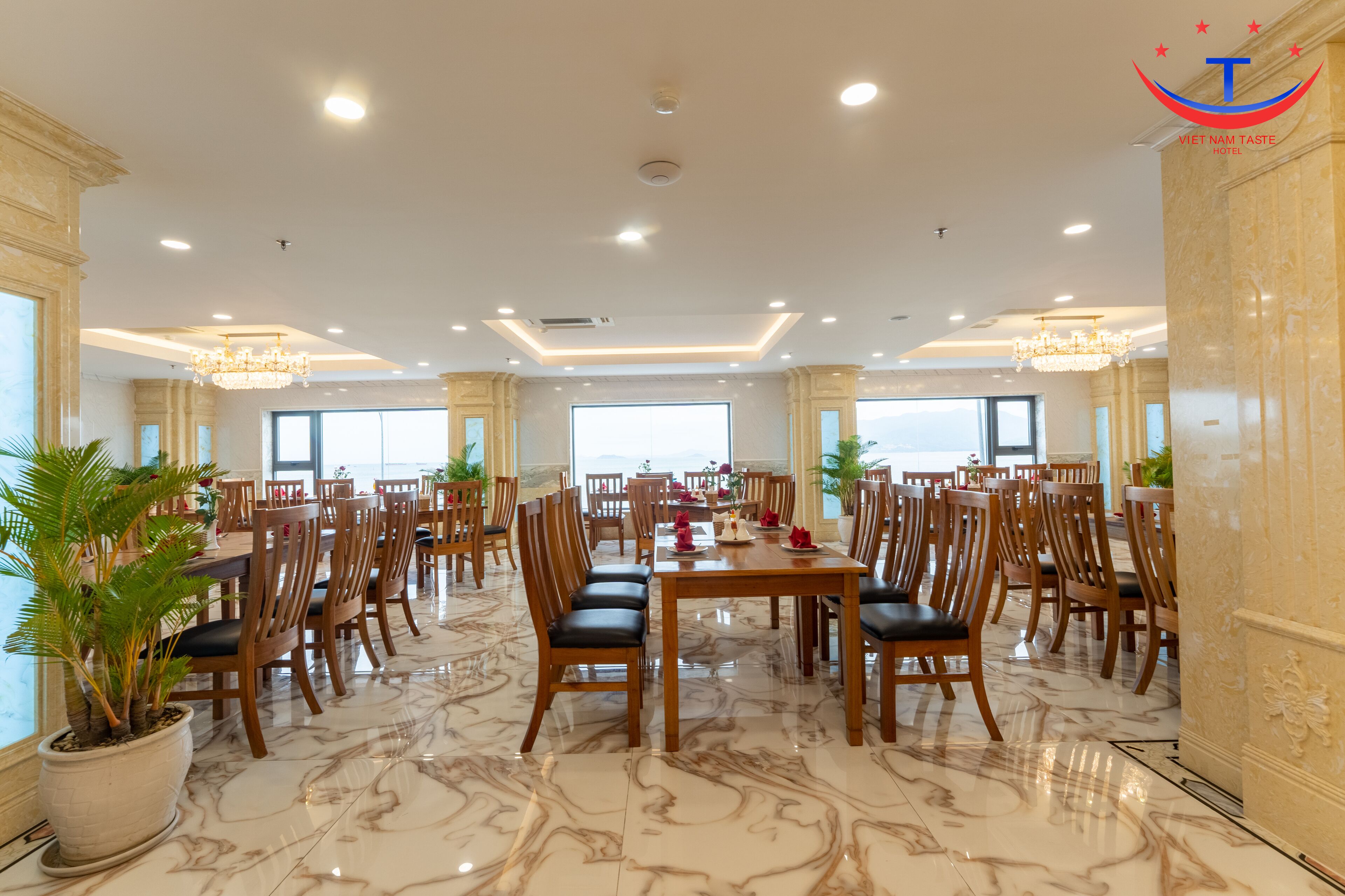 Un comedor espacioso con pisos de mármol, mesas y sillas de madera, y ventanas grandes que ofrecen vistas.