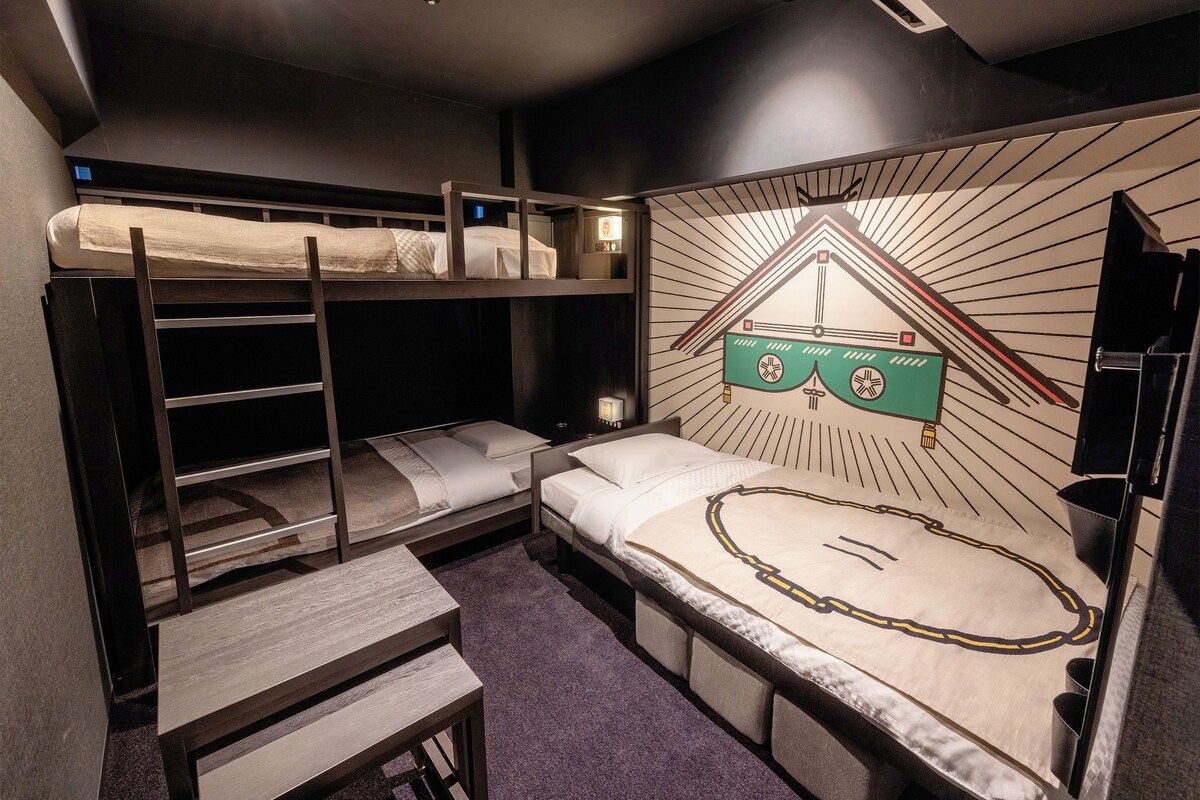 A bunk bed room with a small table and a wall-mounted TV.