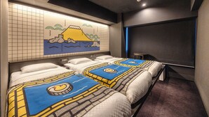 A hotel room with two beds, a large wall mural, a flat-screen TV, and a small table.