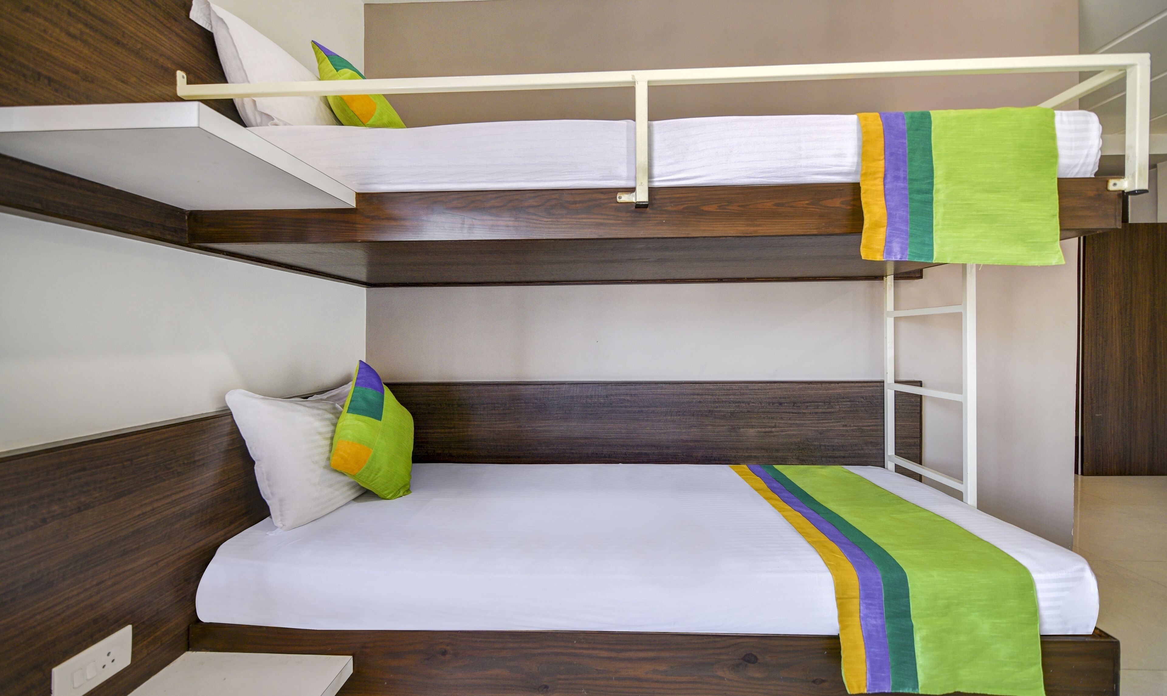 Ein Stockbett mit weißer Bettwäsche und bunten Kissen.