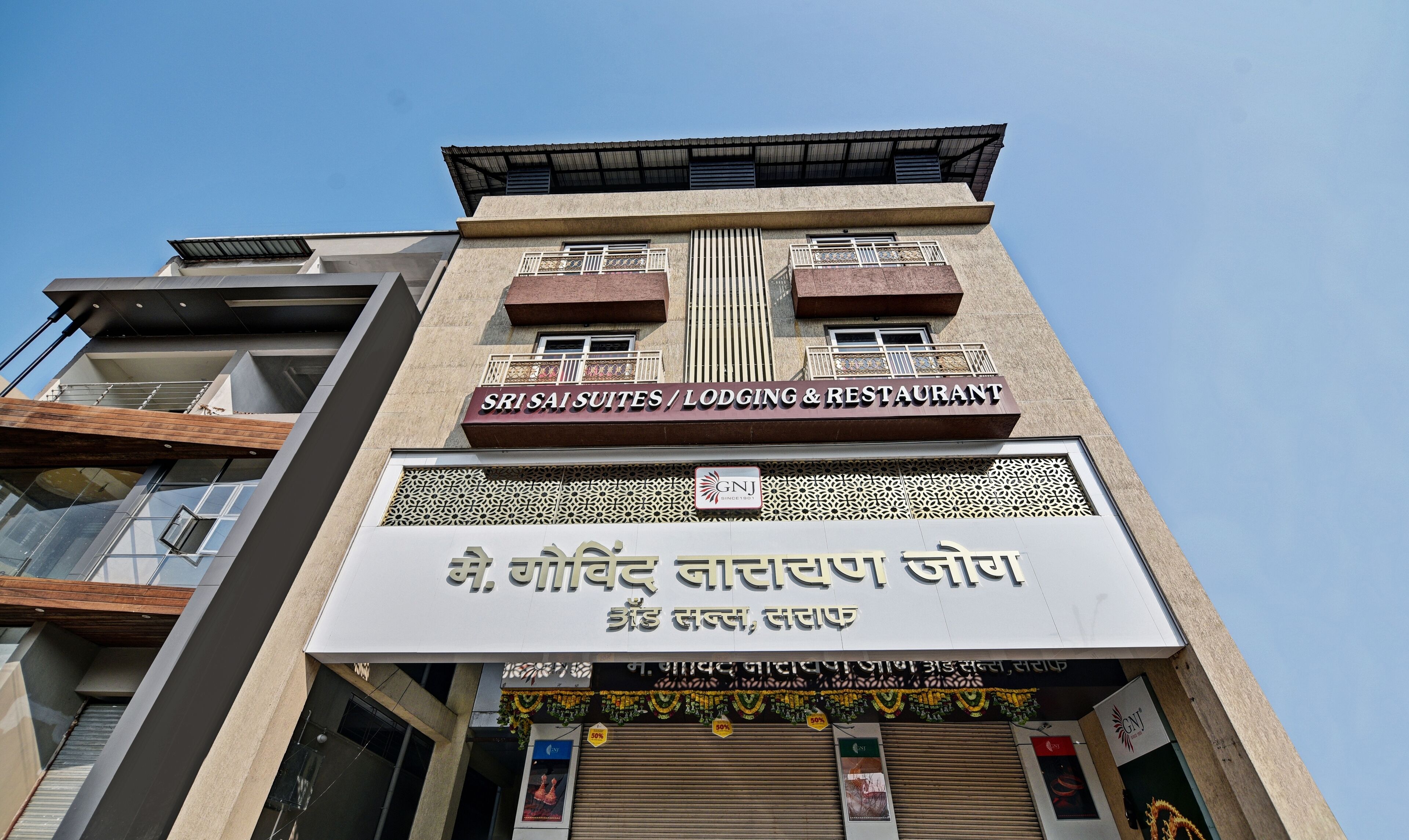 Un bâtiment portant une enseigne indiquant « Sri Sais Suites / Hébergement et restaurant ».
