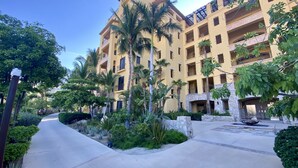 Un hotel de varios pisos con balcones, palmeras y un patio central.