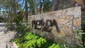 Un muro de piedra con el letrero "HACIENDA Beach Club", que indica un resort u hotel.