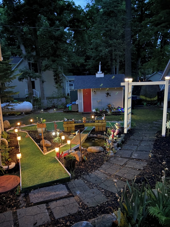 A garden with a pond, stepping stones, and a wooden deck.