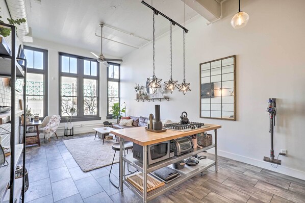 Een moderne keuken met een centraal eiland, grote ramen en hangende ster-vormige lampen.