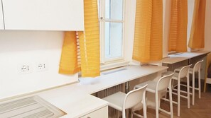 Eine moderne Küche mit weißen Schränken, einem eingebauten Herd und einem Fenster mit gelben Vorhängen.