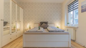 A bedroom with a bed, a wardrobe, a window, and a radiator.