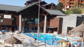 Ein Poolbereich mit einem Gebäude im Hintergrund, einer Rasenfläche im Vordergrund und einem strahlend blauen Himmel.