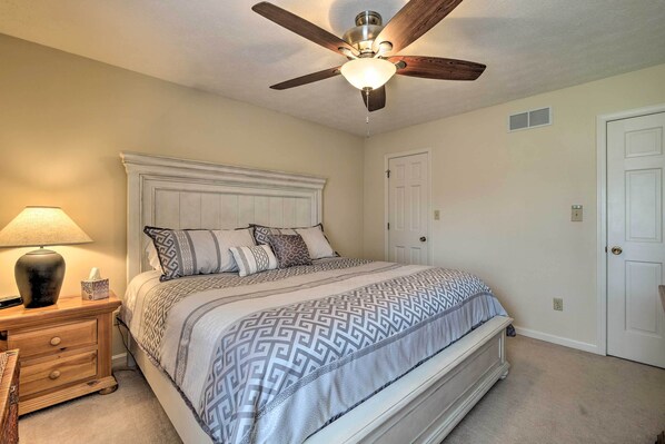 A bedroom with a bed, a nightstand, a lamp, a ceiling fan, and a door. - Lexington Home ~ 2 Mi to University of Kentucky! (Lexington)