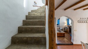 Una scala in pietra conduce a una zona giorno con un divano, un caminetto e un pavimento a scacchi.
