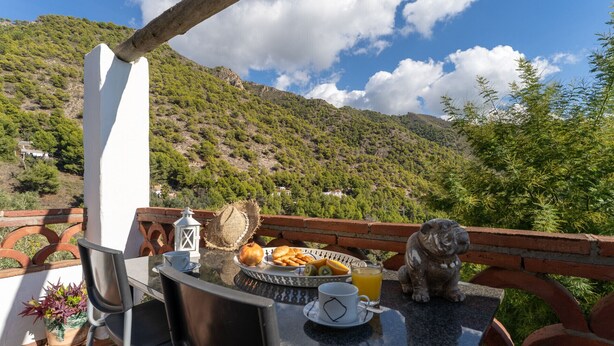 Una terrazza con un tavolo apparecchiato per la colazione, affacciata su un paesaggio montuoso.