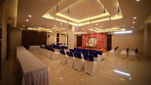 A conference room with a long table, rows of chairs, and a stage with a floral backdrop.
