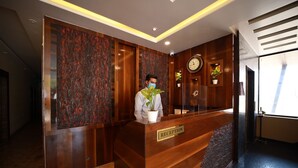 A reception desk with a wooden finish, a clock, and a potted plant.