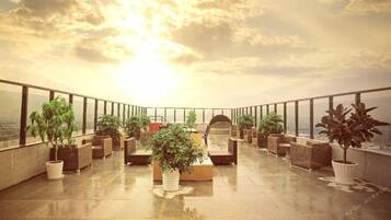 A rooftop terrace with potted plants, seating areas, and a view of the cityscape.