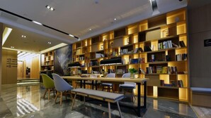 A modern library with marble floors, wooden bookshelves, and comfortable seating areas. - Atour Hotel (Hangzhou)