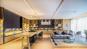 A modern living room with a central seating area, bookshelves, and a dining table. - Atour Hotel (Hangzhou)
