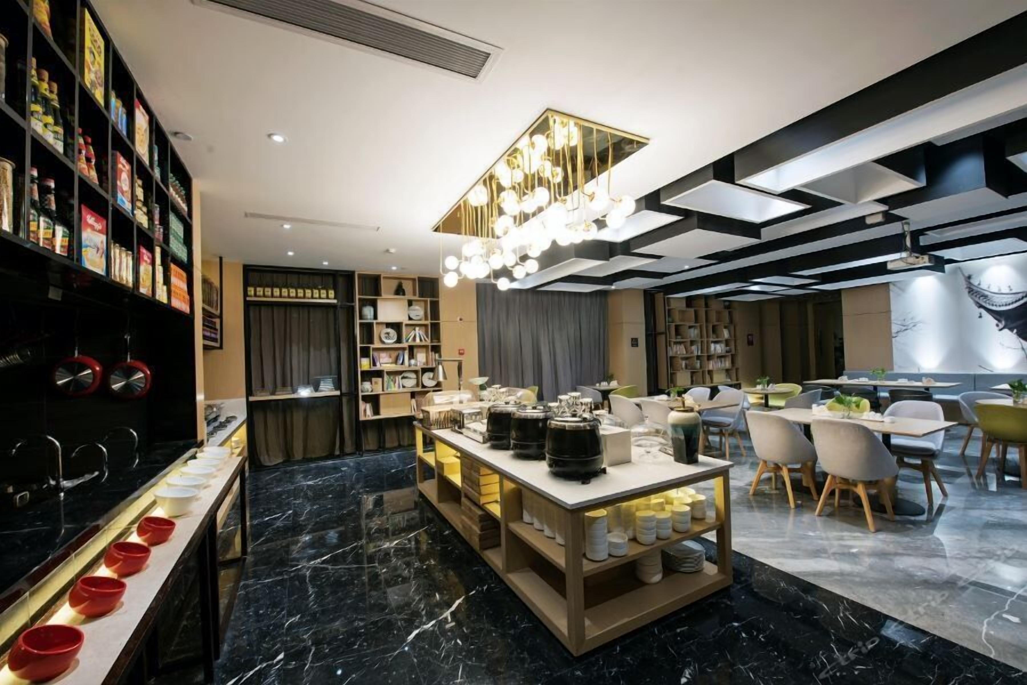 A modern hotel lobby with a marble floor, a central serving area, and a dining area with chairs and tables.