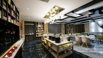 A modern hotel lobby with a marble floor, a central serving area, and a dining area with chairs and tables.
