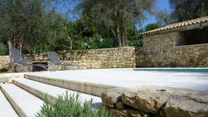 A stone pool with steps leading into it, surrounded by a stone wall and greenery. - Superb house with heated pool in a beautiful garden (Le Rouret)