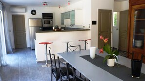 A modern kitchen with a central island, bar stools, and a dining table. - Superb house with heated pool in a beautiful garden (Le Rouret)