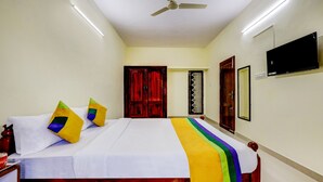 A hotel room with a bed, a ceiling fan, a TV, and a door. - HOTEL UMAIYYAL INTERNATIONAL (Nagercoil)