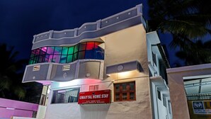 A modern building with a unique curved facade, a prominent sign for UmaiYal Home Stay, and a visible life insurance company sign. - HOTEL UMAIYYAL INTERNATIONAL (Nagercoil)