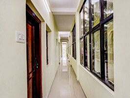 Un pasillo largo y estrecho, con puertas a un lado y ventanas amplias al otro.