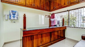 A room with wooden cabinets, a water dispenser, a window with bars, and a counter with a computer. - HOTEL UMAIYYAL INTERNATIONAL (Nagercoil)