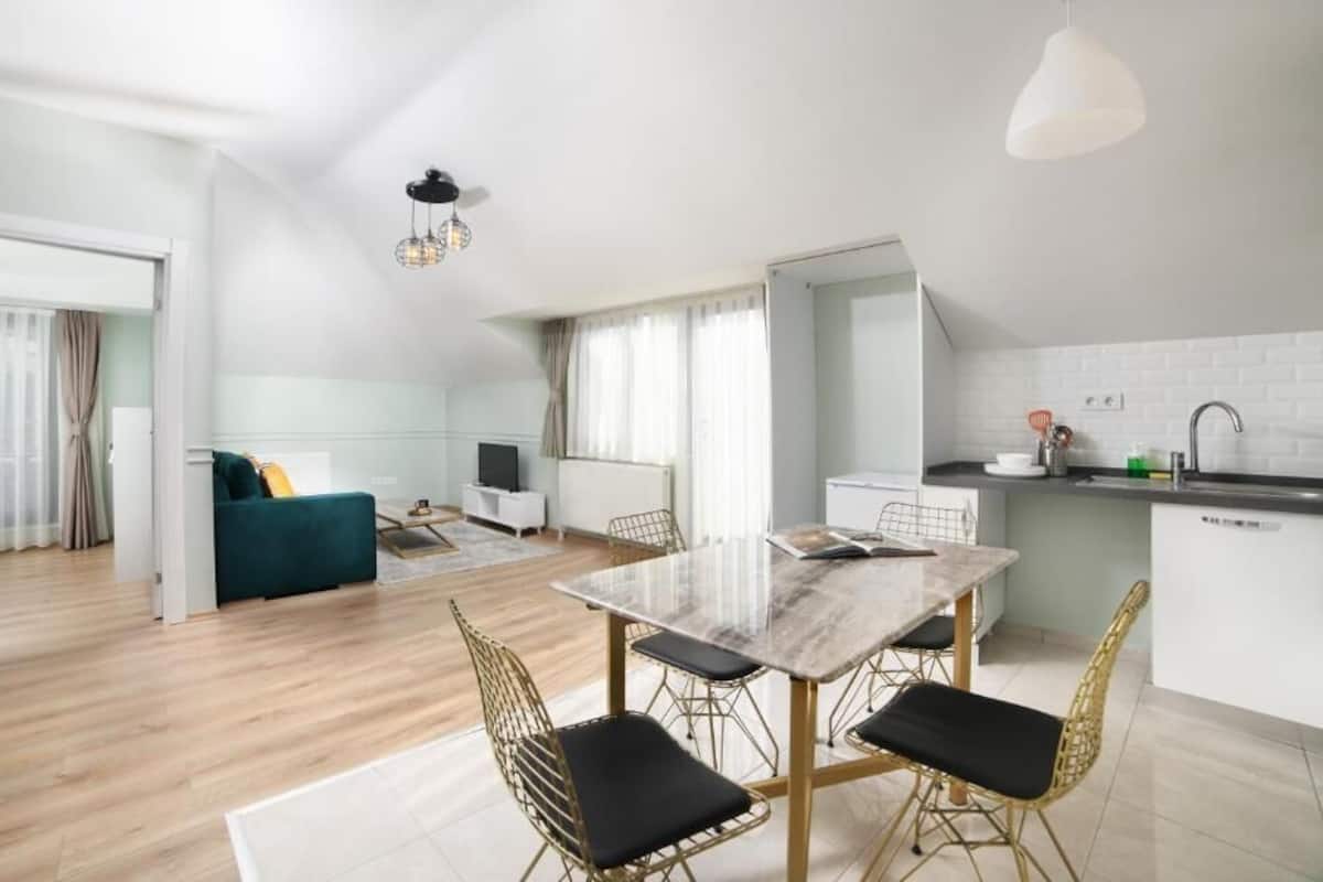 A modern apartment with a dining area, kitchen, and living space.