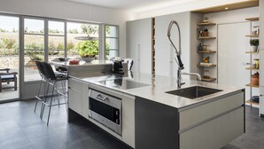 A modern kitchen with a large island, bar stools, and a view of the outdoors. - Exclusive Cortijo surrounded by an olive grove (Arcos de la Frontera)