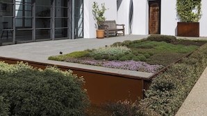 A modern white building with large windows, a patio area with plants, and a clear blue sky. - Exclusive Cortijo surrounded by an olive grove (Arcos de la Frontera)