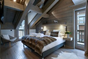 Un dormitorio moderno con una cama grande, vigas de madera, un tragaluz y vistas al exterior.