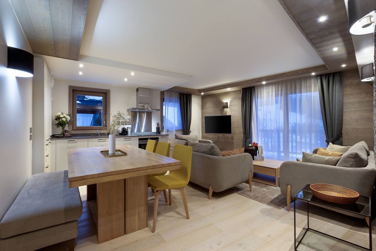 Ein modernes Wohnzimmer mit einem Holzesstisch, gelben Stühlen und einem grauen Sofa.