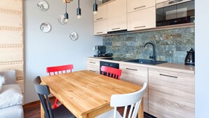 Cozinha moderna com armários de madeira, painel de backsplash de pedra, cafeteira e pia.