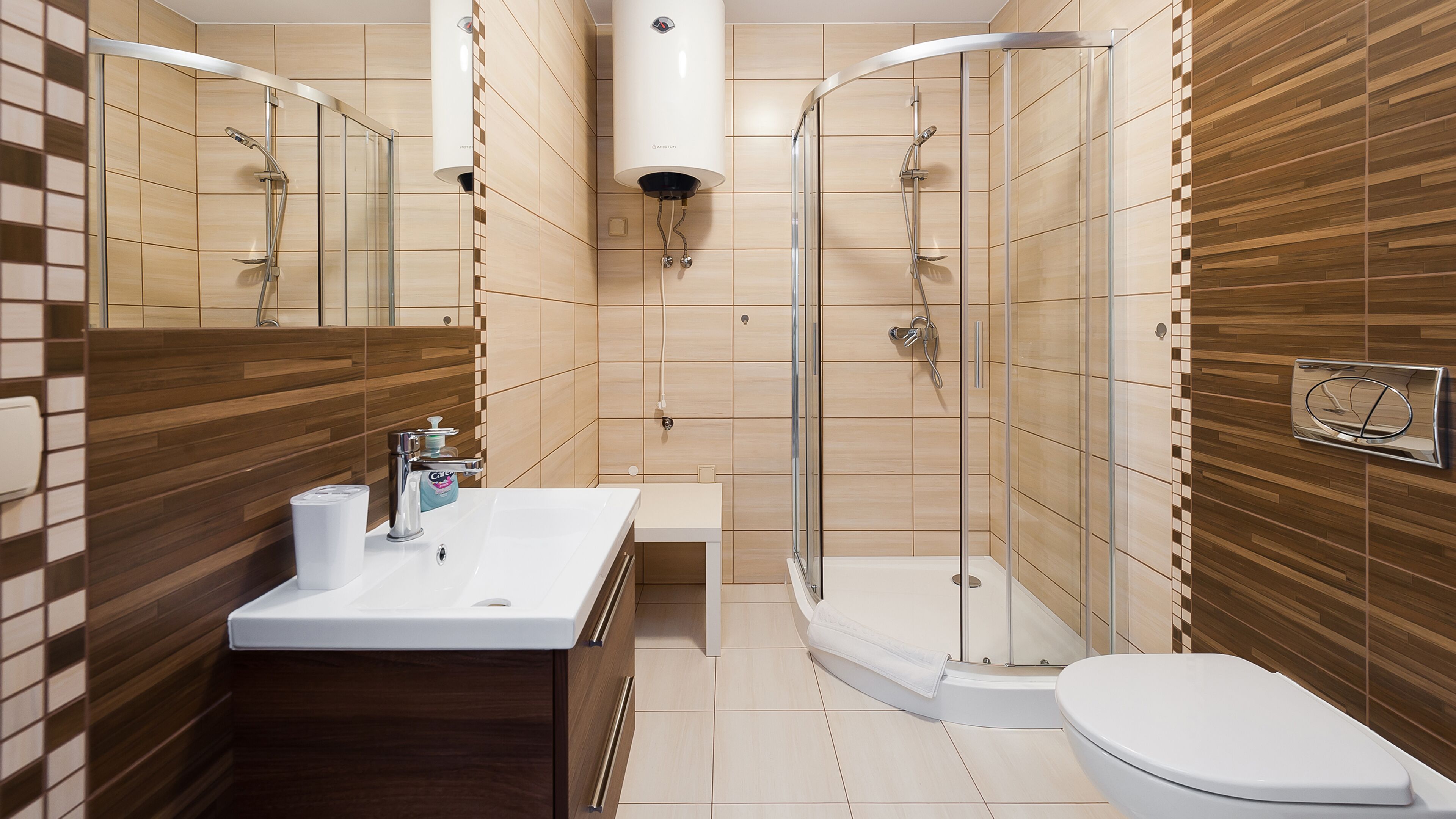 A modern bathroom with a wooden vanity, a glass shower enclosure, and a toilet.